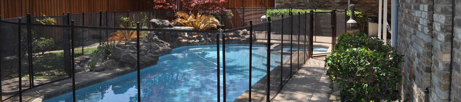 black fence on a swimmingpool and flowers around it