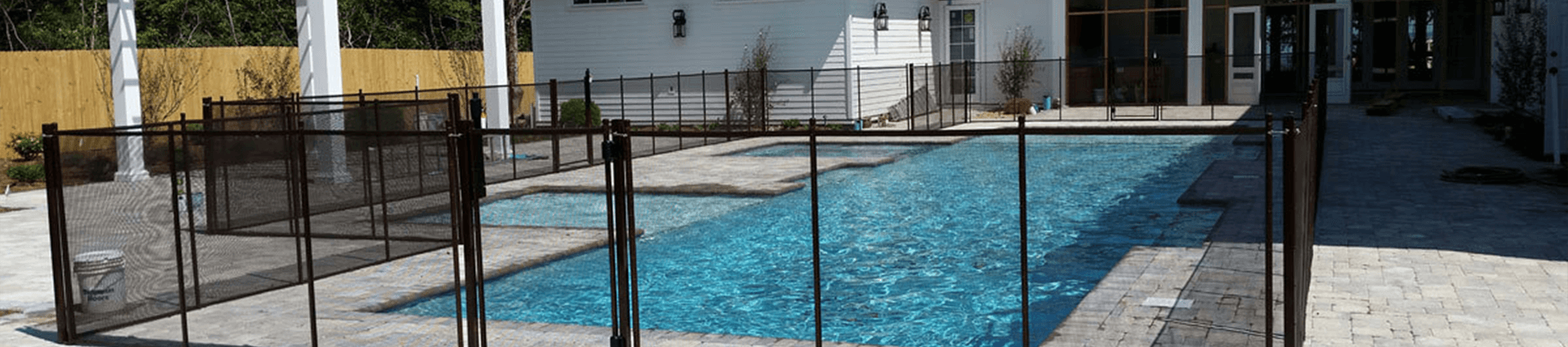 black fence on a swimming pool with white house in the background